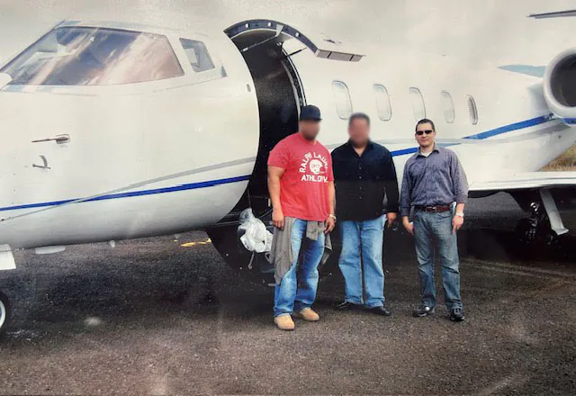 Three men standing beside a private jet on an airfield
